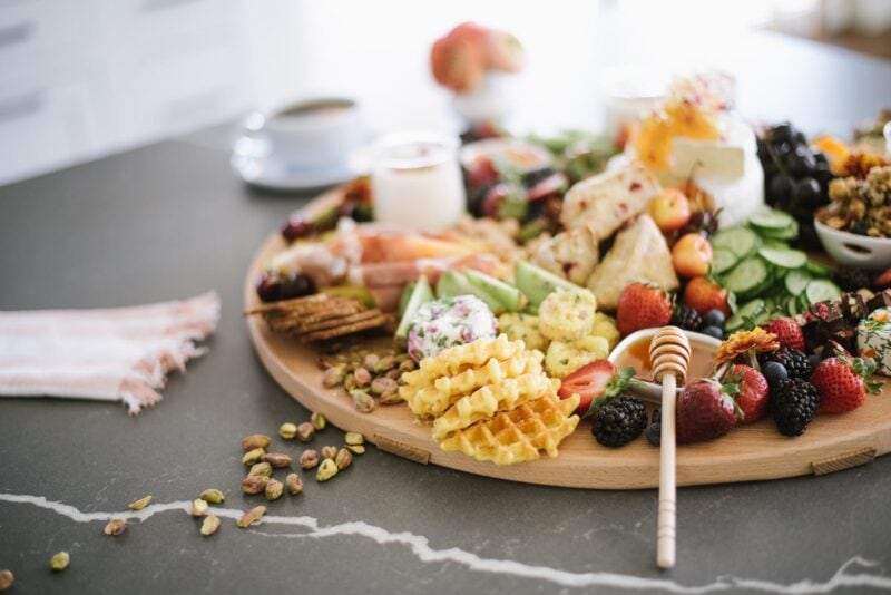 tray with waffles and berries with sweets and cucumber slices