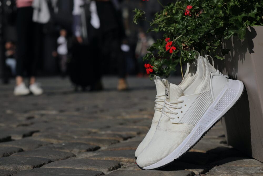 Loom white trainers propped up