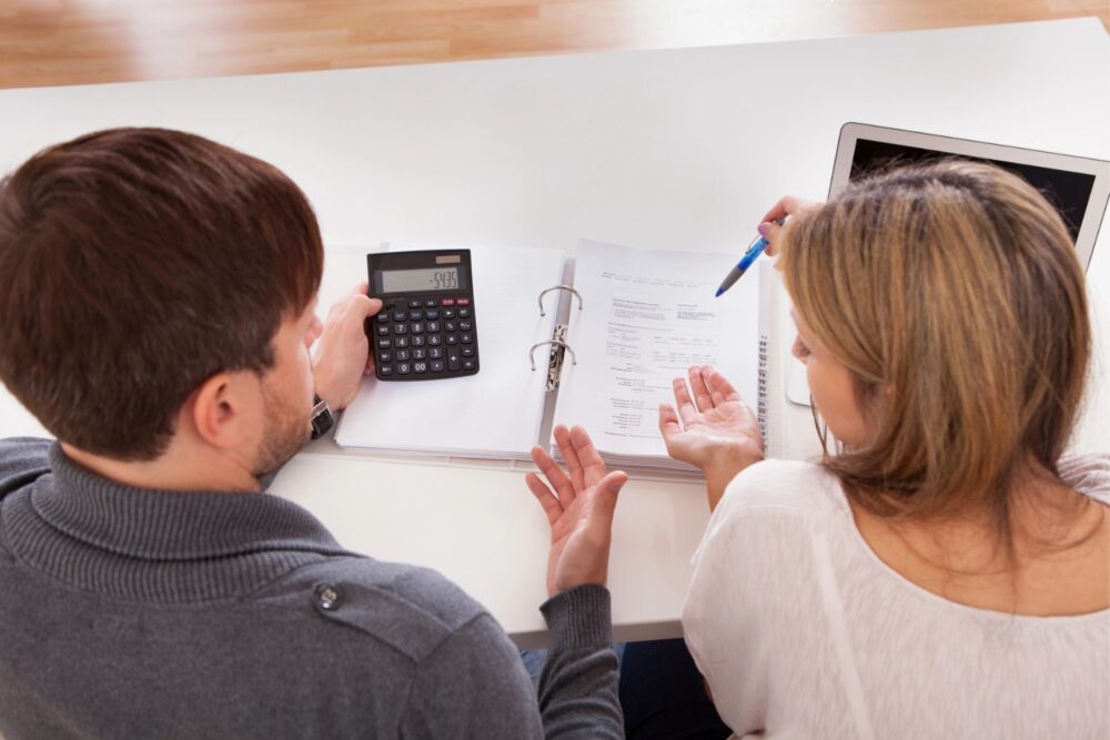 Couple talking about finances with a notebook and laptop in front of them