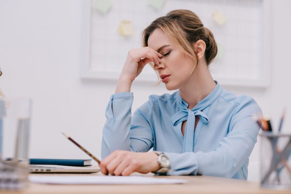 Female business woman looking stressed while working at a laptop