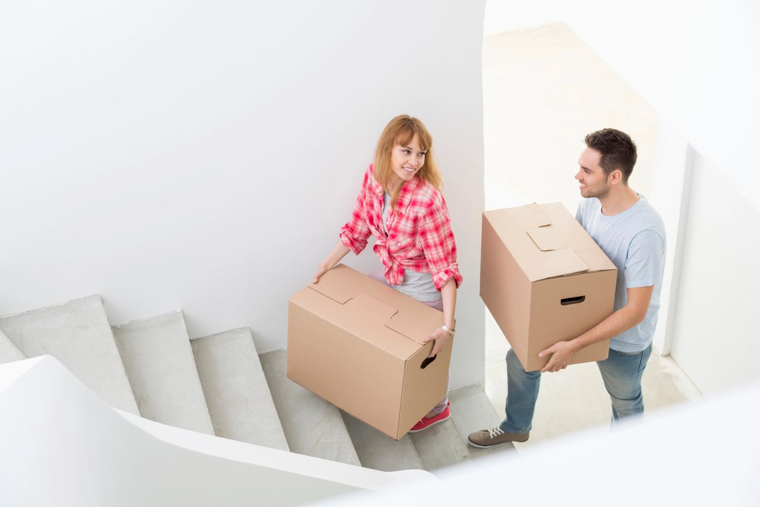Couple carrying boxes up stairs in a new home