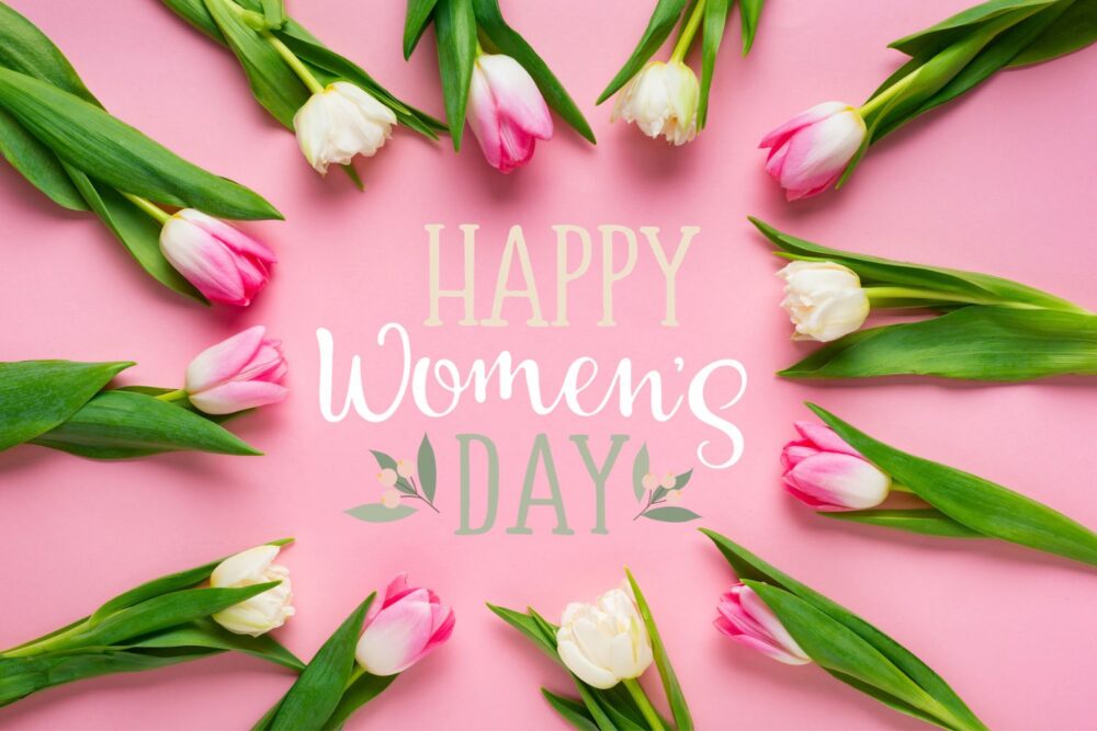 Top view of tulips arranged in frame with happy womens day illustration
