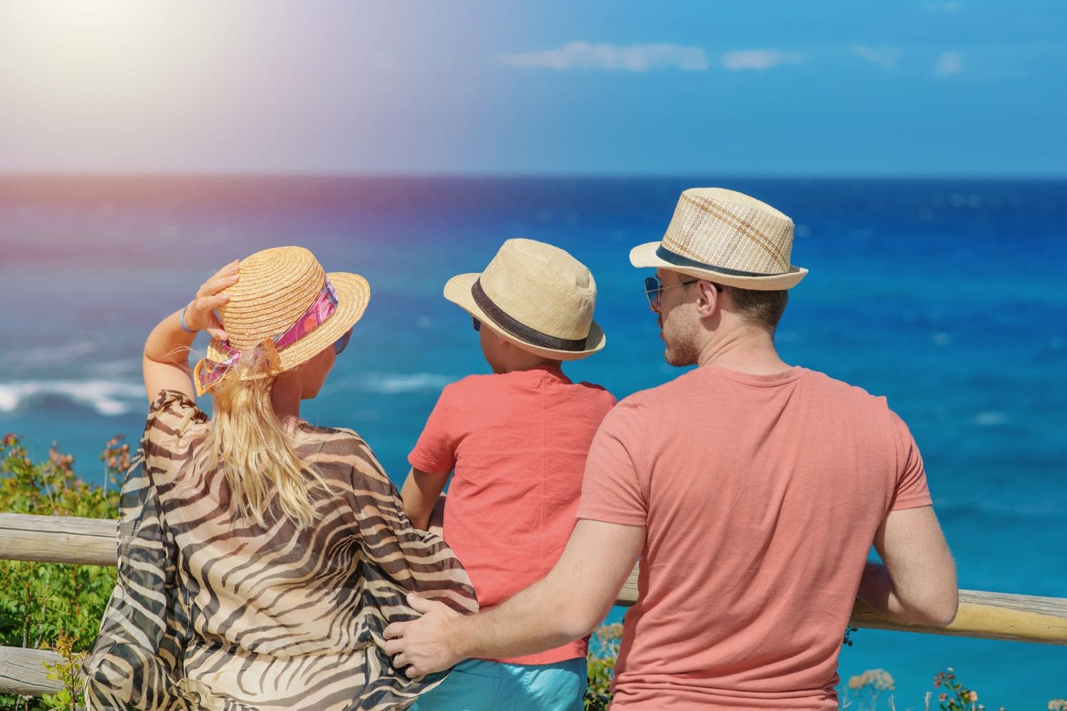 Beautiful European family in sunhats standing on mountain against a wavy sea