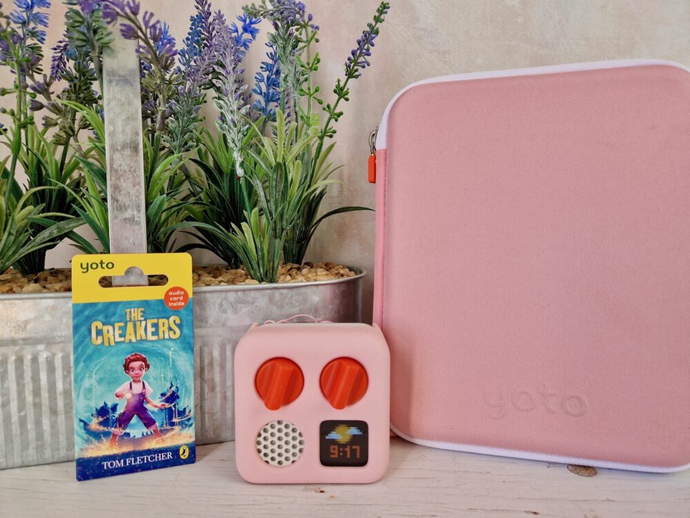 The Creakers Yoto Card in front of purple flowers and next to a Yoto Mini player and a card folder