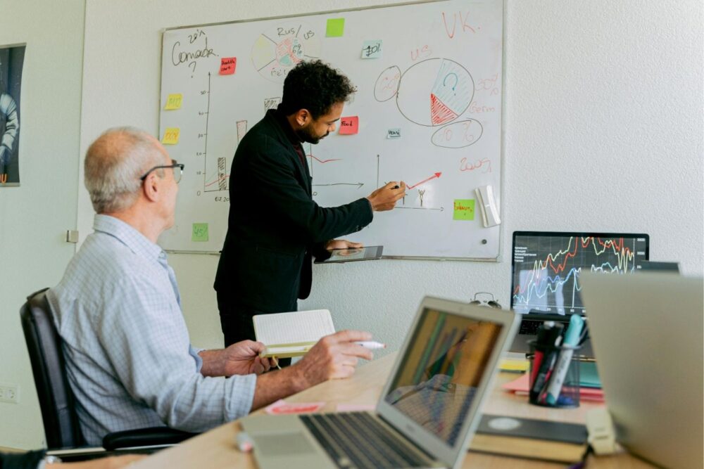 Two men in an office with a whiteboard