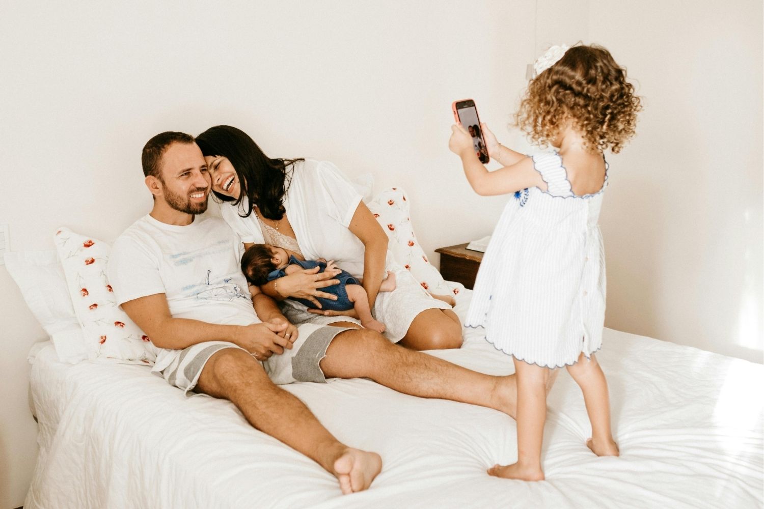 Toddler Taking a Photo of her Parents and sibling on a bed
