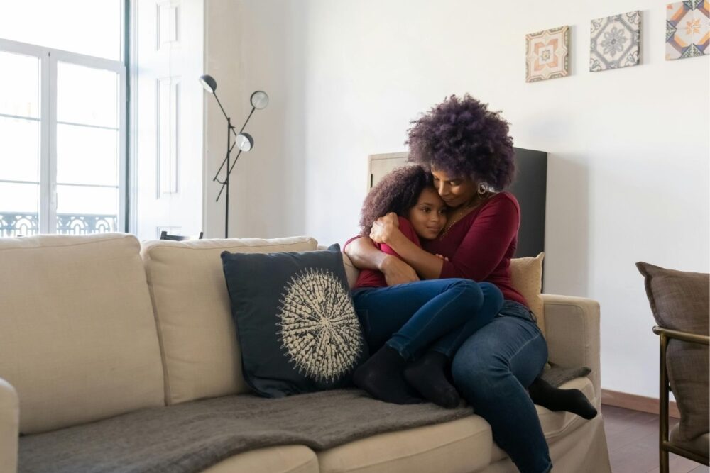 Woman Sitting in a Couch Hugging her Daughter