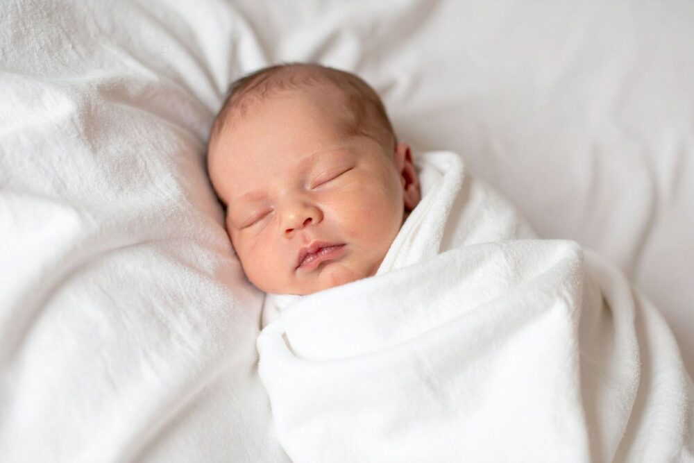 Sleeping newborn baby swaddled in a white blanket